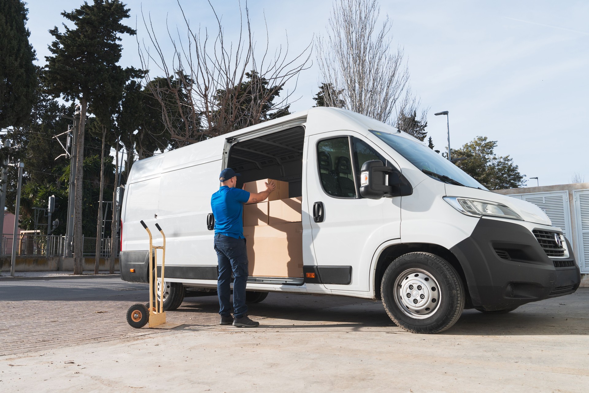 Delivery Worker Loading Boxes into White Van Outdoors