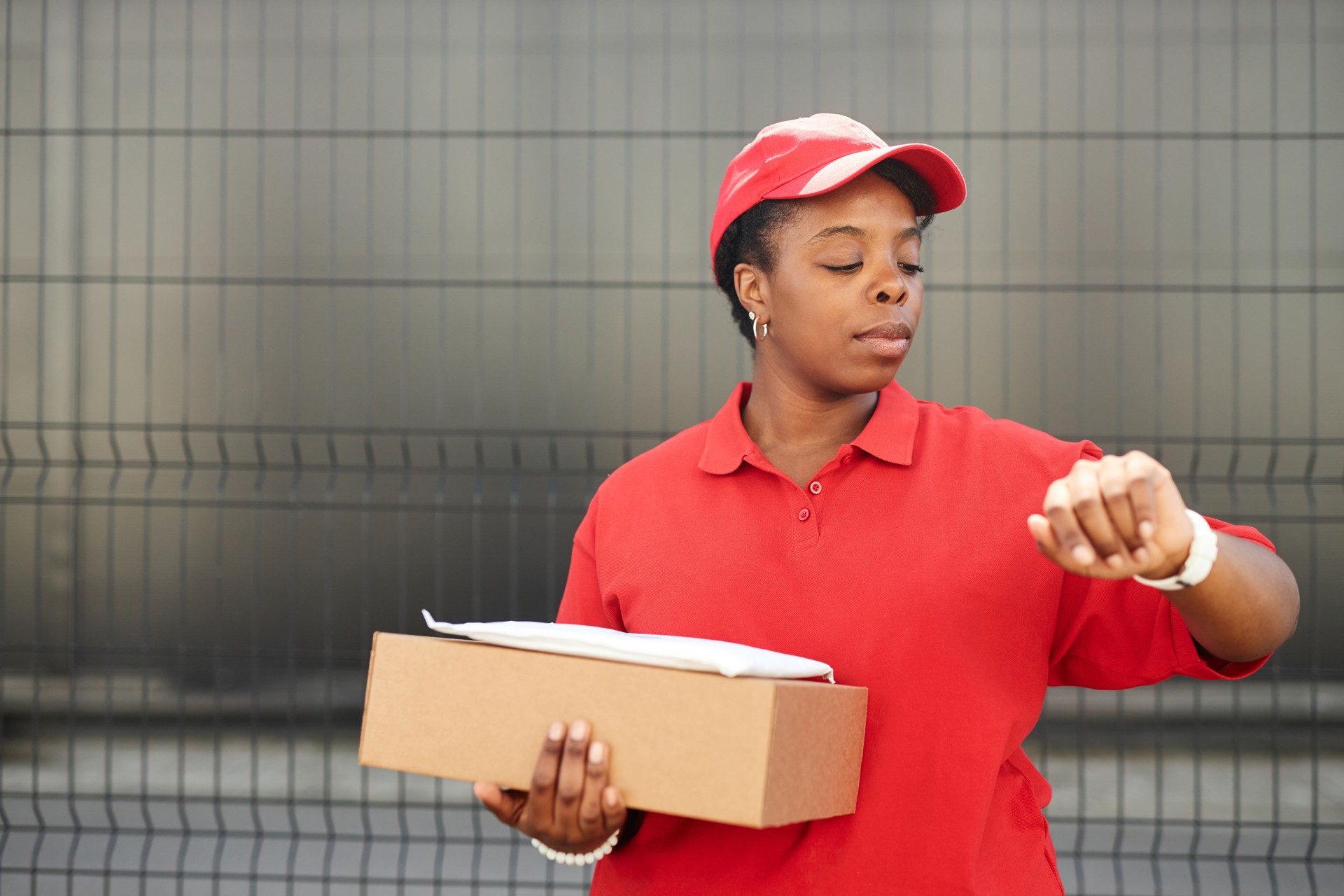 Checking Time While Holding Package in Red Uniform